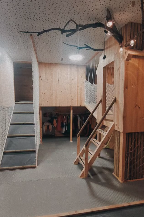 Casa na árvore com escadas, ramos e luzes no teto