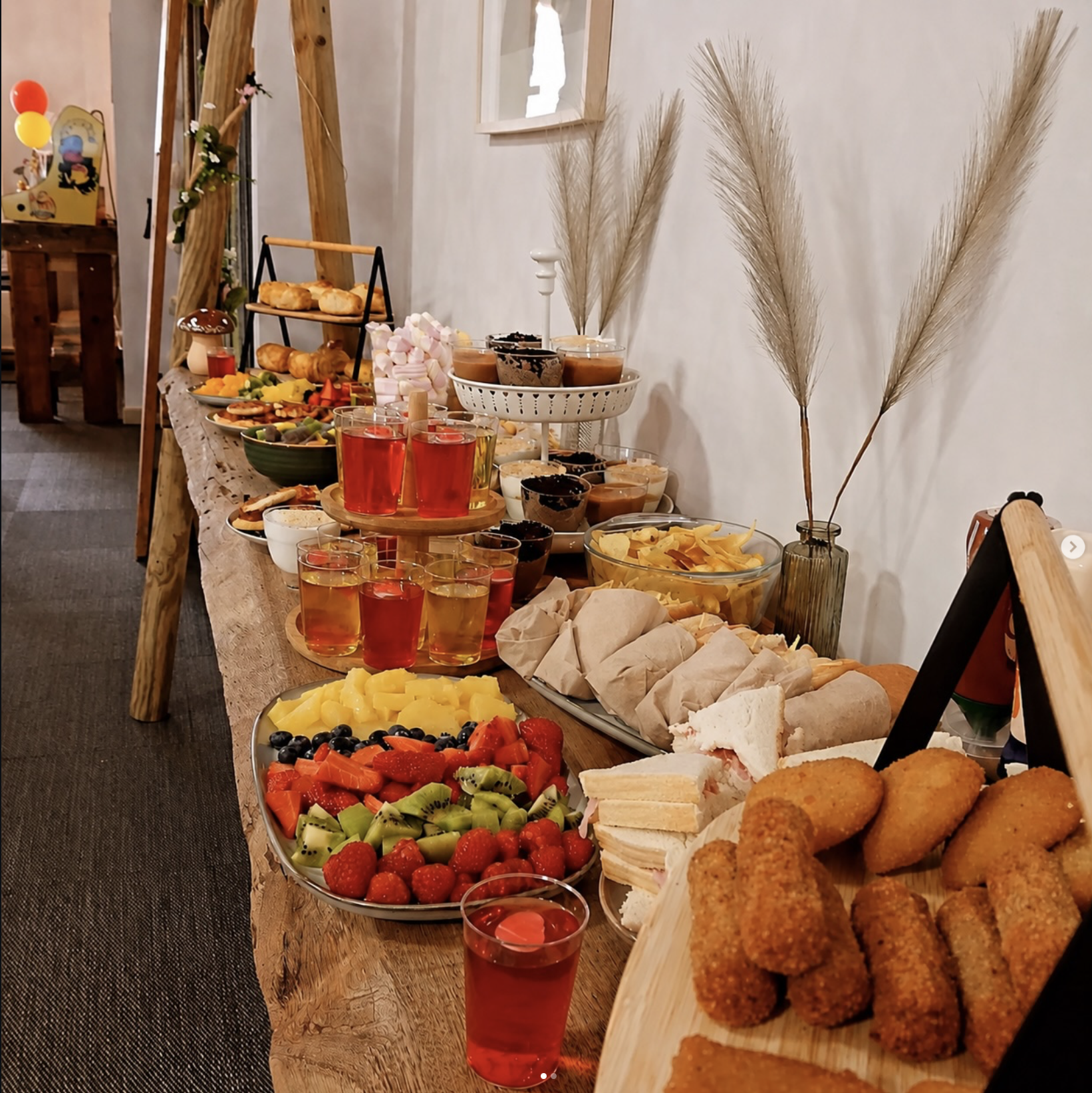 Mesa de festa com fruta, sandes, bolos e sumos